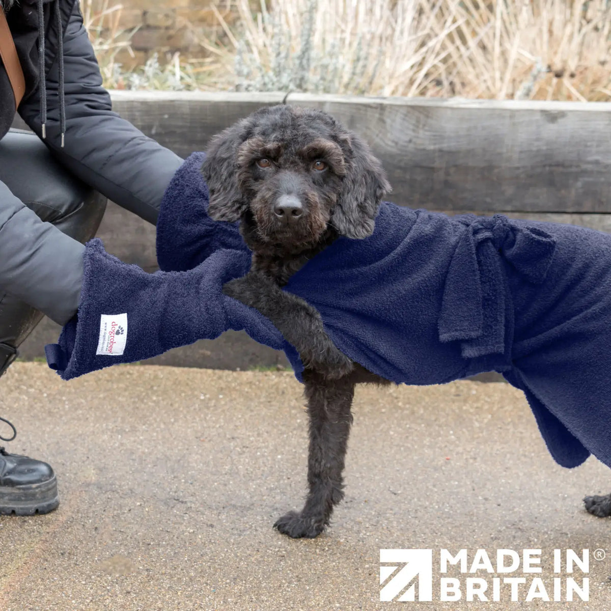 Person using Navy Dogrobes Dog Drying Gauntlets (mitts) to dry a black Labradoodle’s paw, with the dog wearing a matching navy Dogrobe