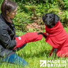 Woman using Red Dogrobes Dog Drying Gauntlets to dry a wet Labrador’s paws while dog wearing red Dogrobe and Snood