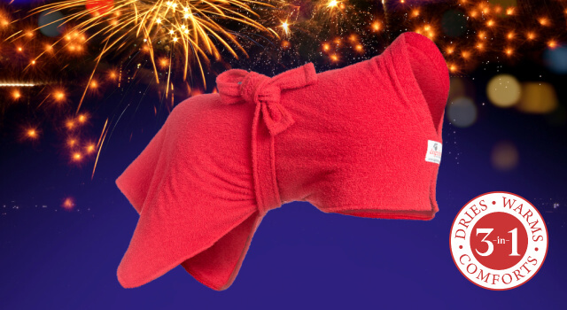 A Red Dogrobe against a fireworks background. The 3-in-1 dog drying coat dries, warms and comforts.
