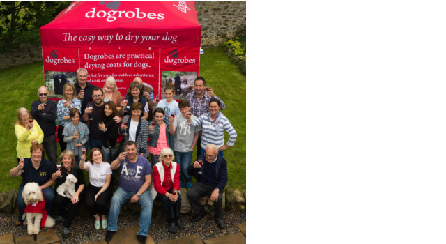 The Dogrobes’ team outside with glasses raised celebrating 10 years birthday and Golden Doodle wearing red dog dressing gown.